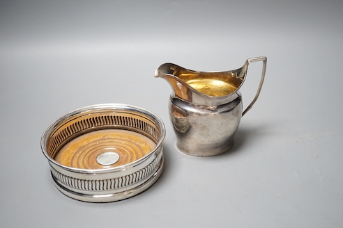A George III silver mounted wine coaster, Sheffield, 1805, diameter 13.2cm and a George III silver cream jug, with later engraved inscription, London, 1801(a.f.).